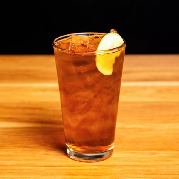 Iced tea with a lemon wedge and ice on a wooden table at Papas and Eggs.